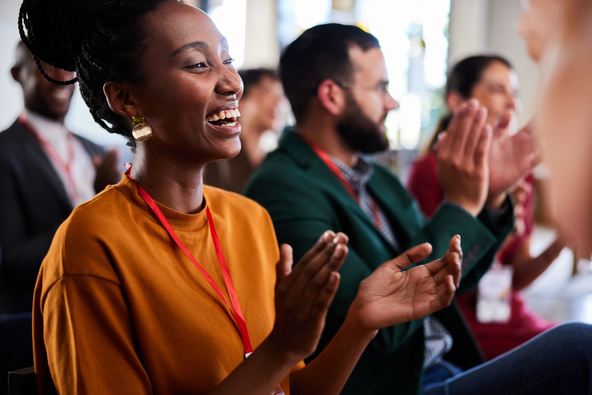 Laughing young businesswoman and colleagues clapping during a seminar at work