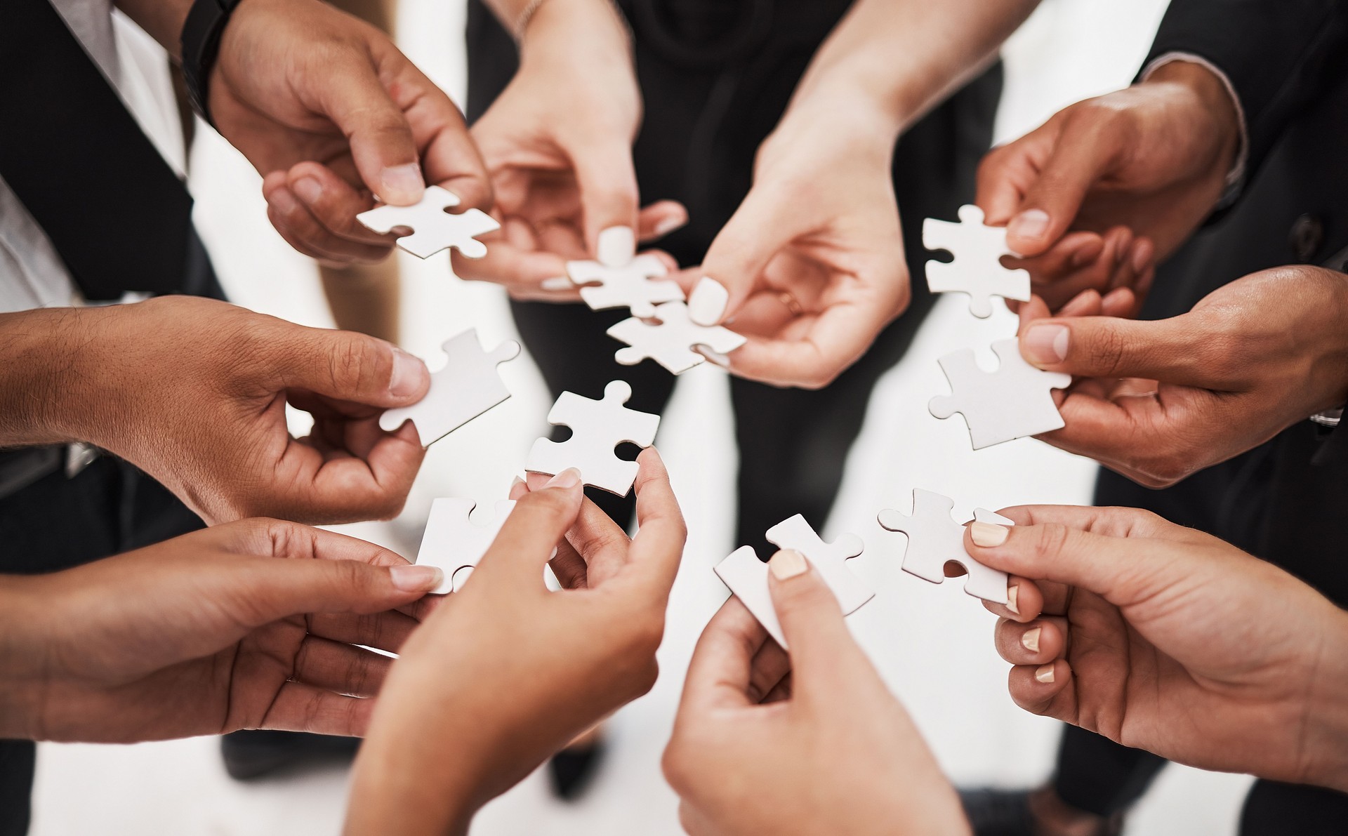 Closeup shot of a group of unrecognisable businesspeople joining puzzle pieces together